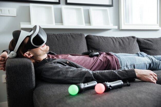 행복한 사람이 집에서 소파에 누워 3D 안경을 착용