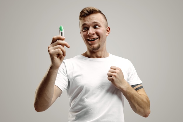 Happy man looking at pregnancy test at studio. Human emotions concepts