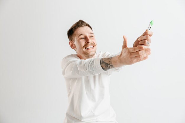 Happy man looking at pregnancy test at studio.