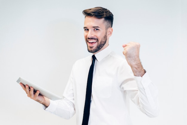 Free photo happy man looking at a tablet with a raised fist