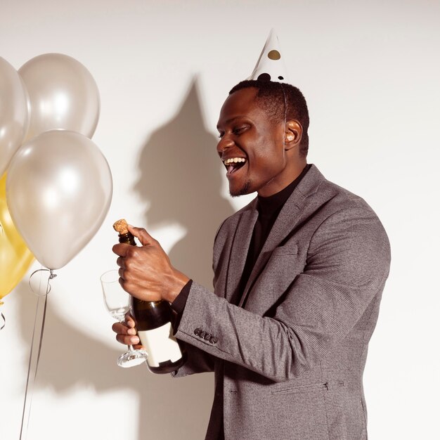 Happy man opening a bottle of champagne