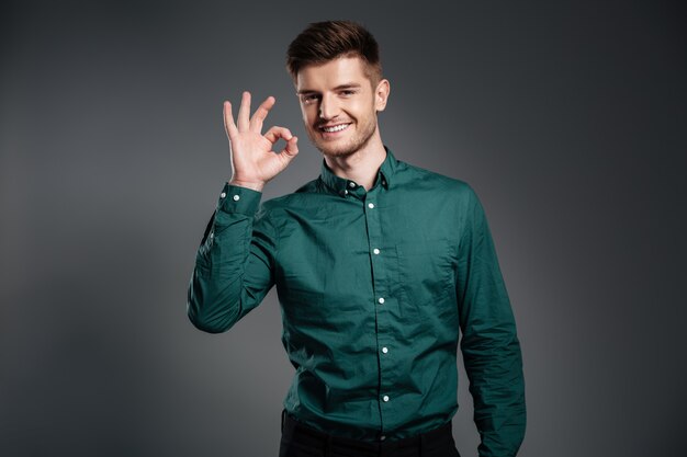 Happy man posing over grey  showing okay gesture.