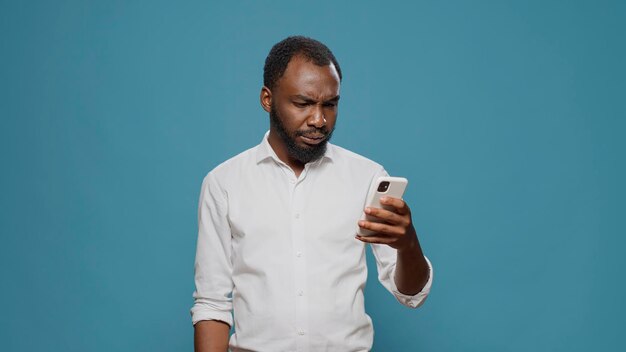 Happy man reading good news on smartphone and celebrating success, feeling overjoyed by work achievement. Cheerful person enjoying victory and win, feeling positive about surprise.