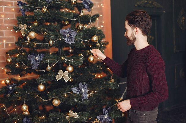 빨간 스웨터에 행복 한 사람입니다. 벽난로 앞의 남자. 크리스마스 트리 배경 남성입니다.
