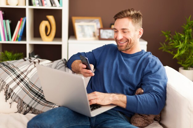 Happy man scanning qr code by mobile phone at home