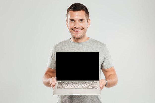 Happy man showing display of laptop computer.