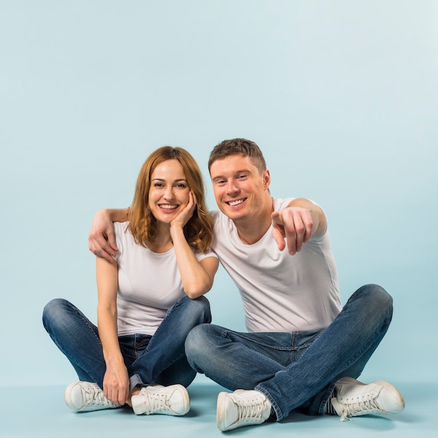 Happy man showing her girlfriend something with pointing his finger to camera