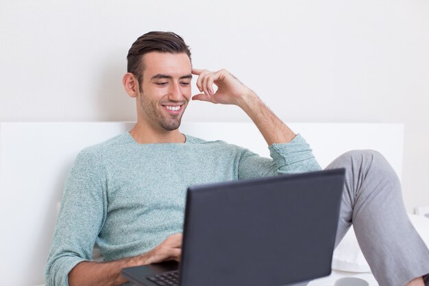 Happy Man Sitting Comfortably on Sofa With Laptop