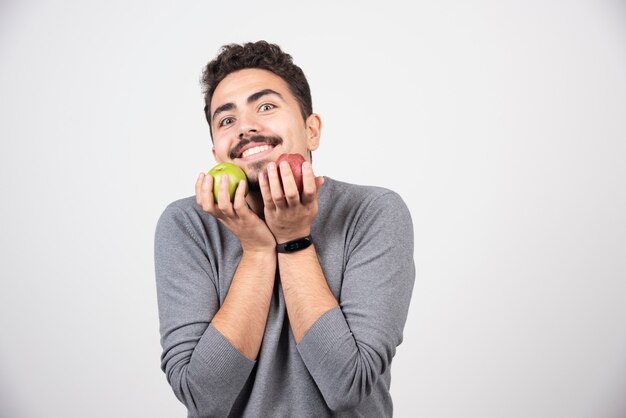 Happy man smiling with apples on gray.