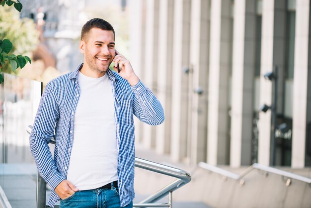 Happy man speaking on phone near banister