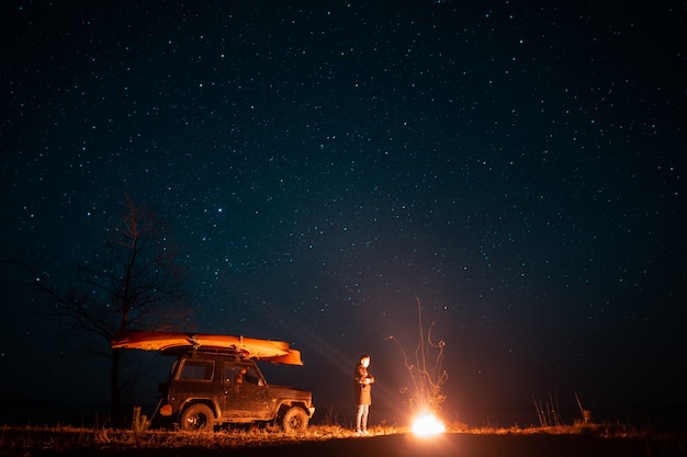 Happy man standing in front burning bonfire