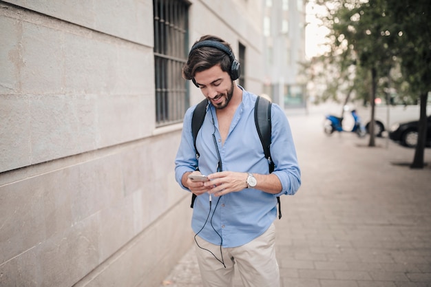 Free photo happy man standing on pavement listening to music