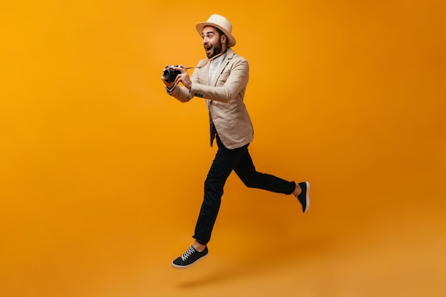 Uomo felice in abito elegante che salta e scatta foto