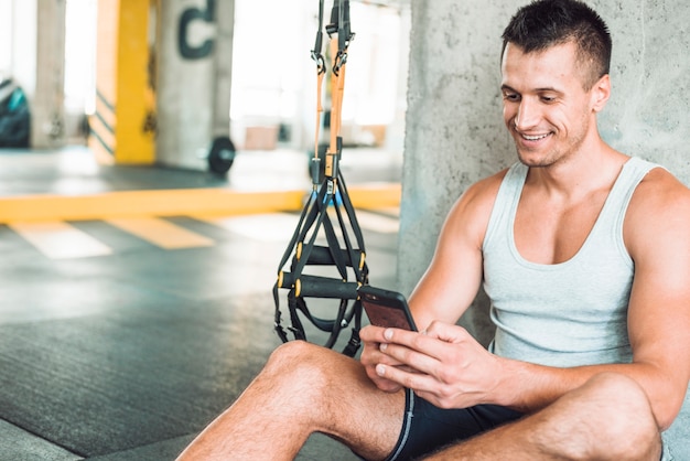 Happy man using cellphone in gym