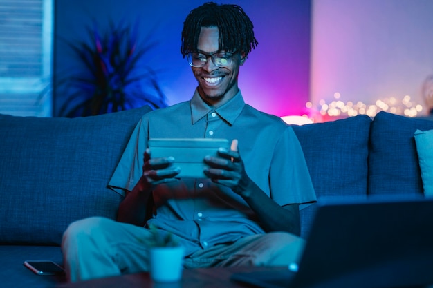 Счастливый человек, используя свой планшет дома на диване