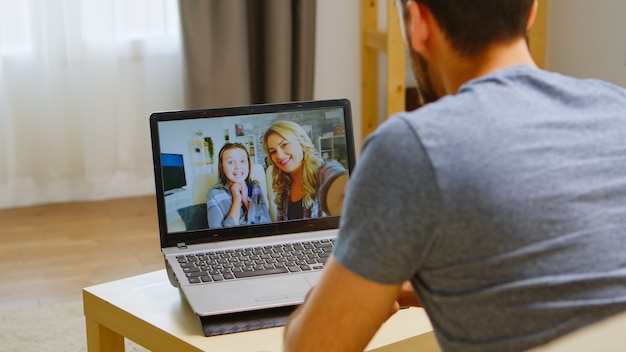 Foto gratuita uomo felice che saluta in videochiamata con la sua famiglia durante la quarantena del coronavirus.