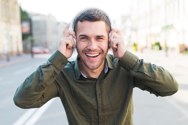 Free photo happy man wearing headphone listening music and looking at camera