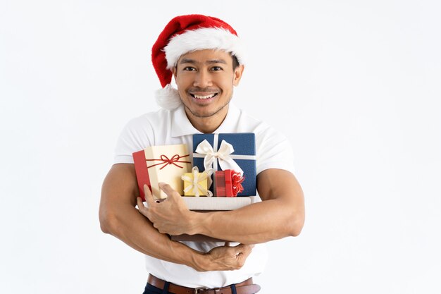 Happy man wearing Santa hat and embracing gift boxes