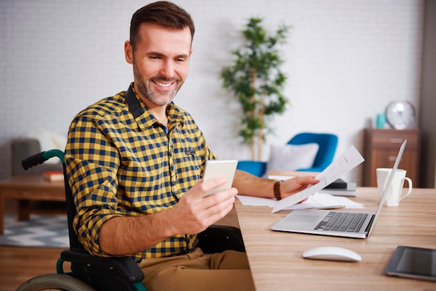 Happy man on wheelchair working at home