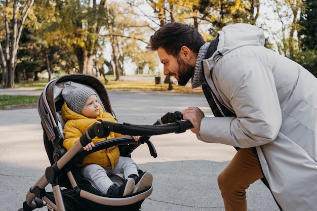 無料写真 ベビーカーの外で彼の子供と幸せな男