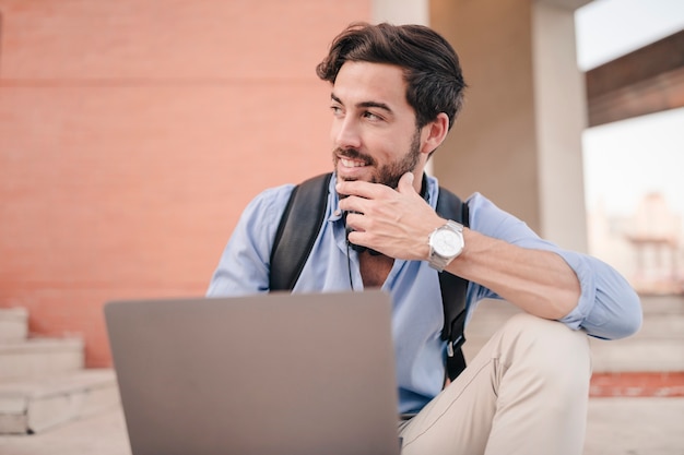 Happy man with laptop looking away