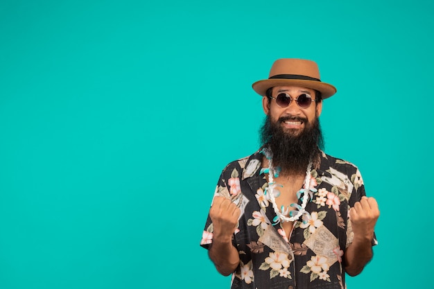 The  of a happy man with a long beard wearing a hat, wearing a striped shirt showing a gesture on a blue .