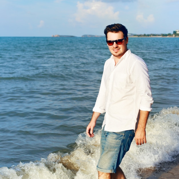 Felice l'uomo con la camicia bianca in riva al mare