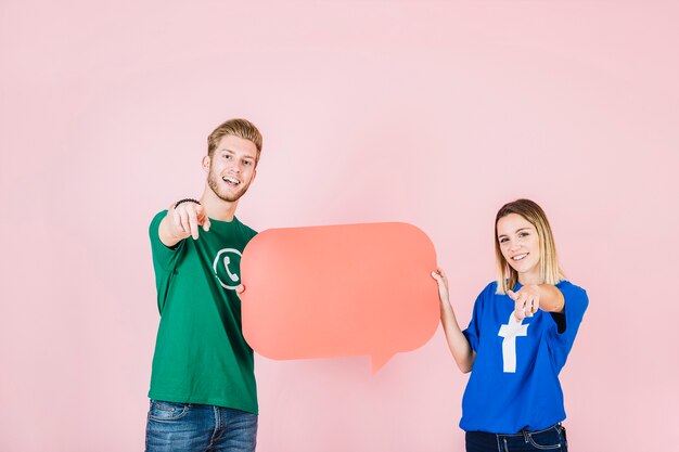 Happy man and woman gesturing while holding empty orange speech bubble