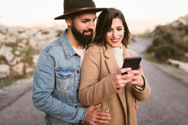 Happy man and woman looking on phone on road