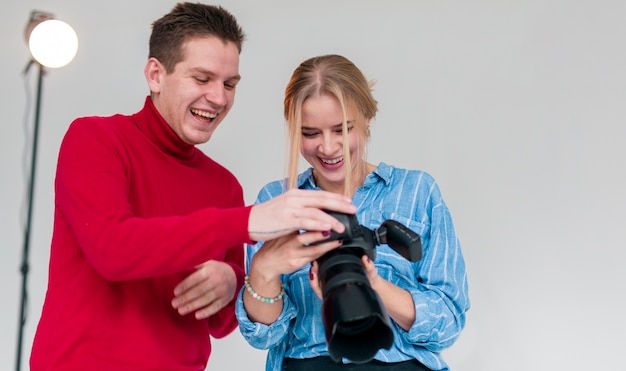 Foto gratuita uomo felice e donna che guardano attraverso le foto in studio