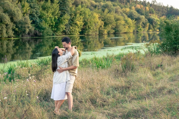 Happy man and woman in nature by the river enjoying each other