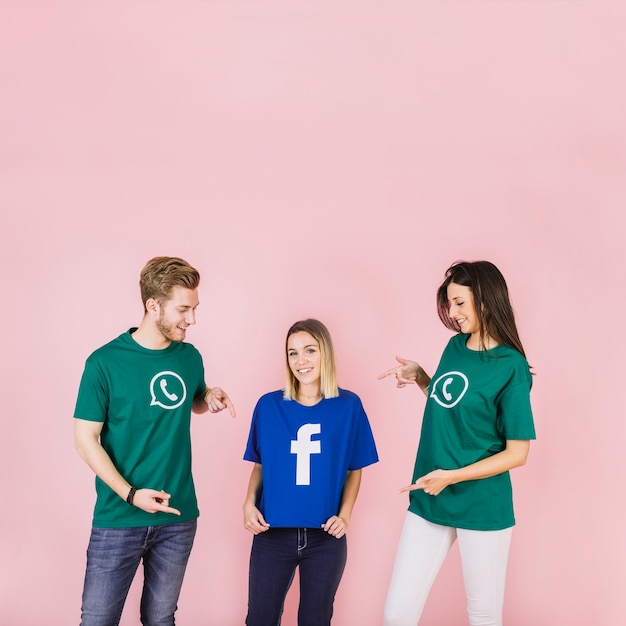 Free photo happy man and woman pointing at her friend using facebook t-shirt