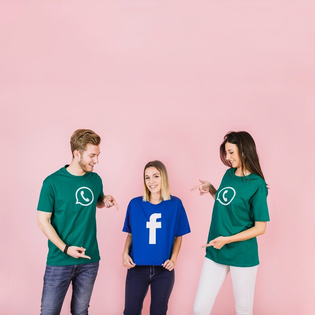 Happy man and woman pointing at her friend using facebook t-shirt