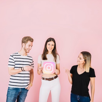 Felice uomo e donna che punta al loro amico tenendo l'icona di instagram