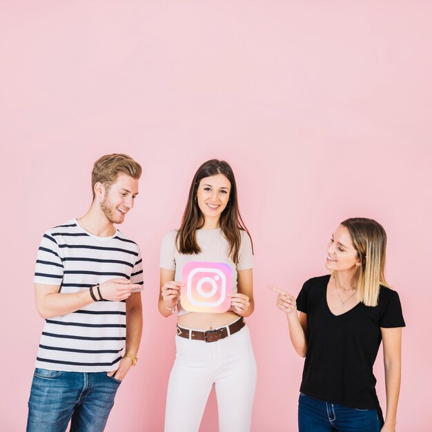 Happy man and woman pointing at their friend holding instagram icon