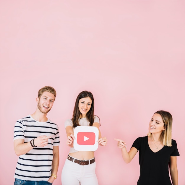 Happy man and woman pointing at their friend showing play icon