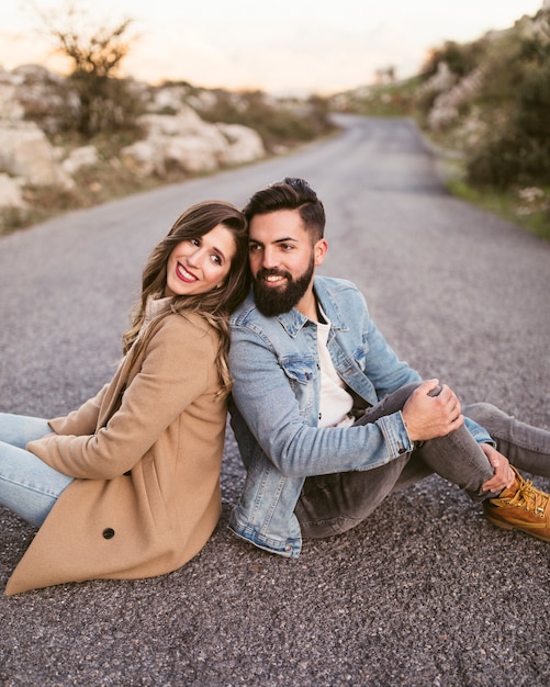 Free photo happy man and woman sitting on road