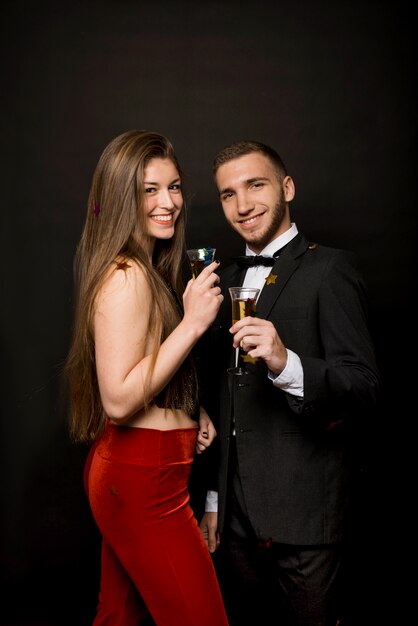 Happy man and woman with glasses of drinks and confetti