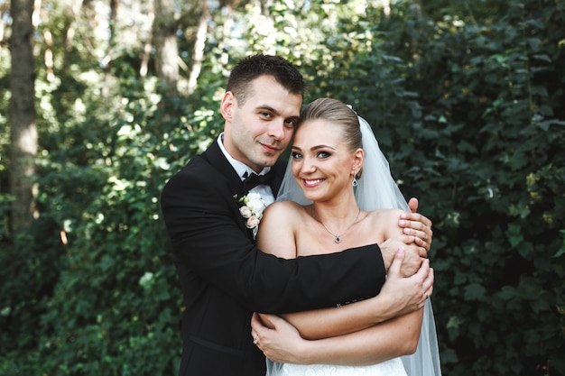 Happy married couple embracing in forest