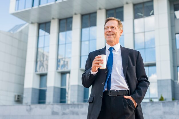 Happy mature businessman holding cup of coffee