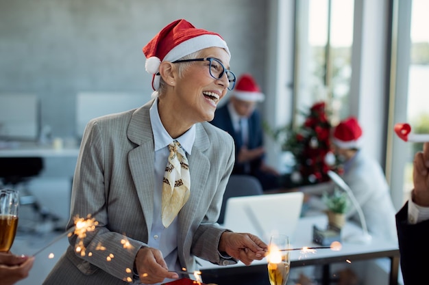 Happy mature businesswoman having fun on New year's party in the office