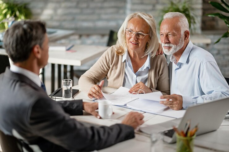 Free Photo happy mature couple talking with real estate agent while analzying housing plans on a meeting in the office
