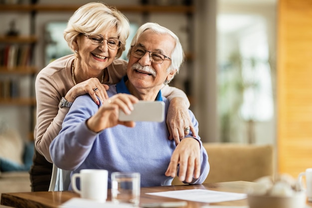 Happy mature couple using mobile phone and having fun while taking selfie