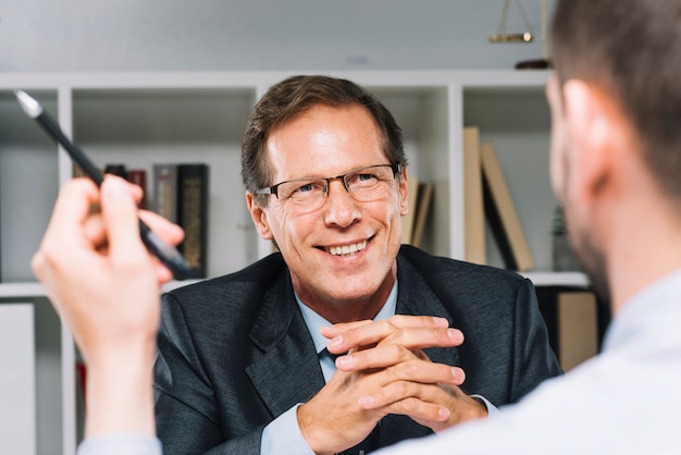 Happy mature lawyer sitting with business customer