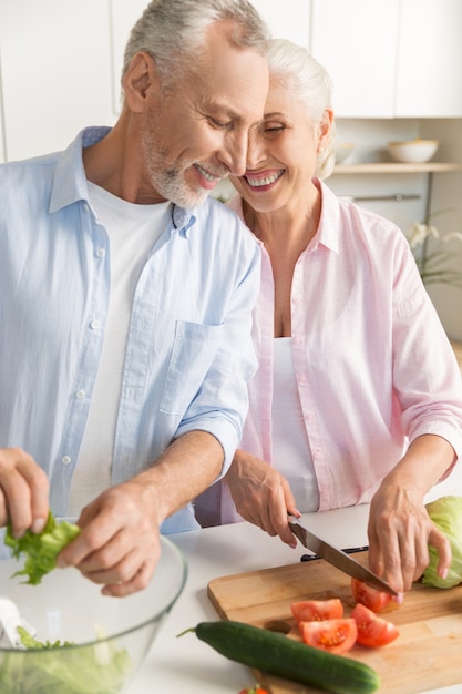 Happy mature loving couple family cooking salad