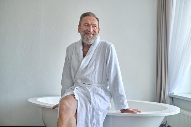 Счастливый зрелый мужчина мечтает в ванной