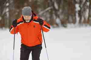 Free photo happy mature man in winter park. senior activewear trekking in the forest at leisure