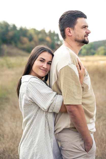 野原に立ちながら抱き合う幸せな成熟した男性と女性