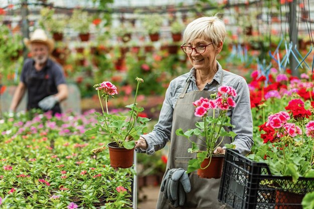 정원 센터에서 꽃과 함께 일하는 동안 즐기는 행복한 성숙한 여성