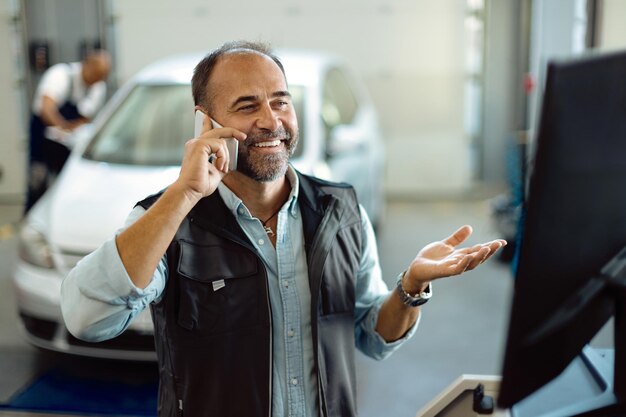 Счастливый механик звонит по телефону во время работы в автомастерской
